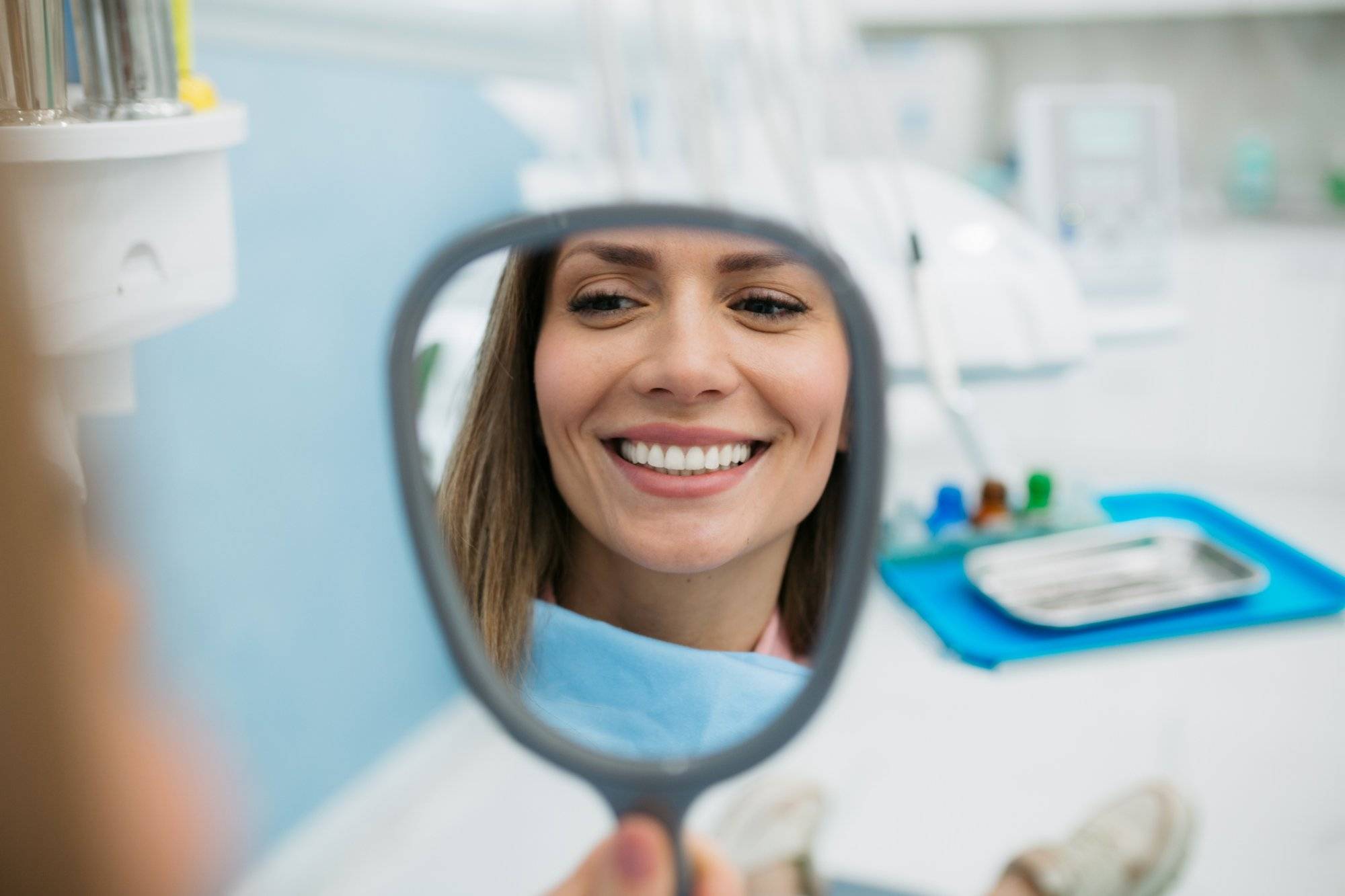 A happy woman looking herself in the hand held mirror Learn How You Can Stay Healthy With These 2023 Carrollton Health Tips