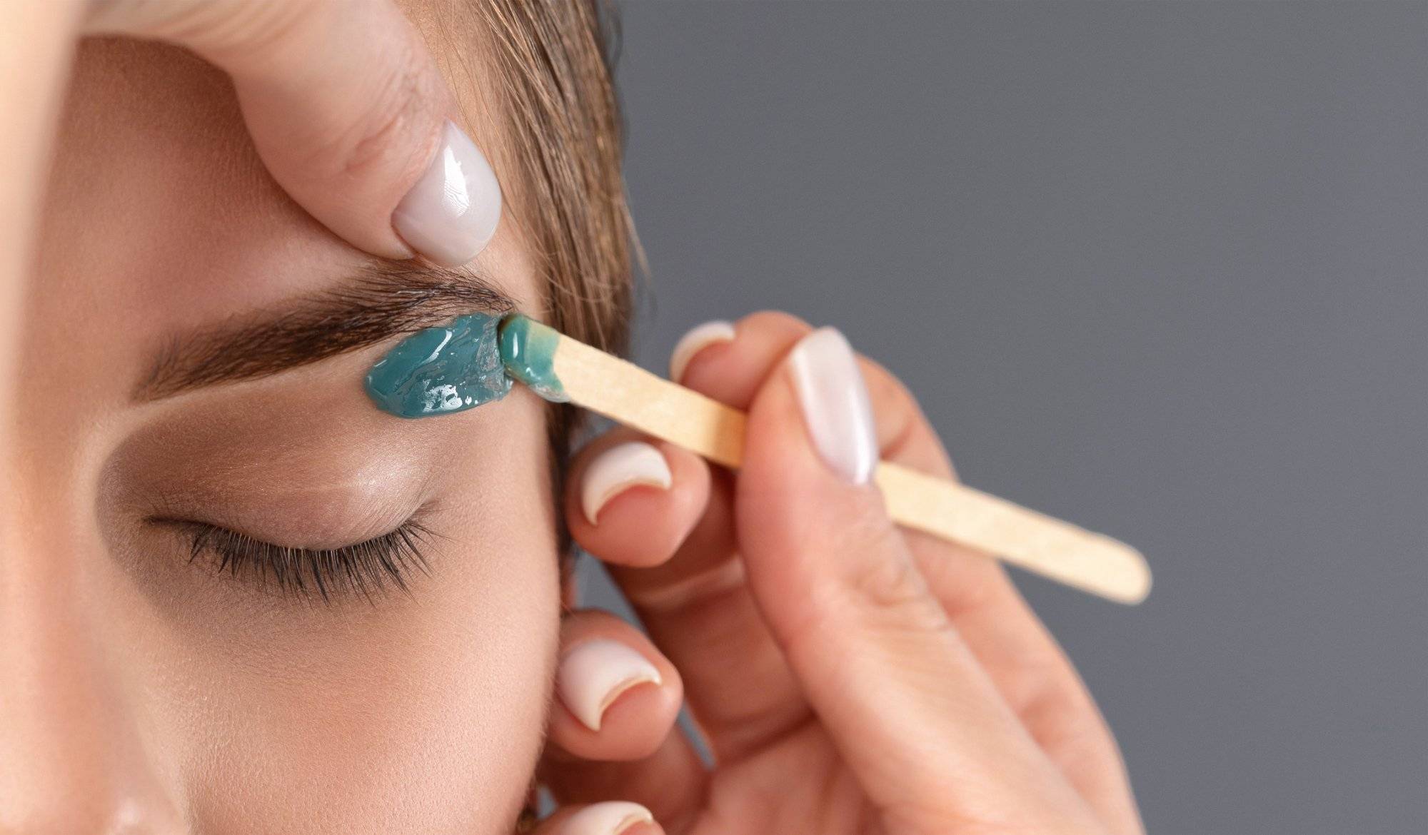 Makeup artist does facial hair removal procedure. Beautiful girl with blue eyes having Permanent Make-up on her Eyebrows.  Professional makeup.