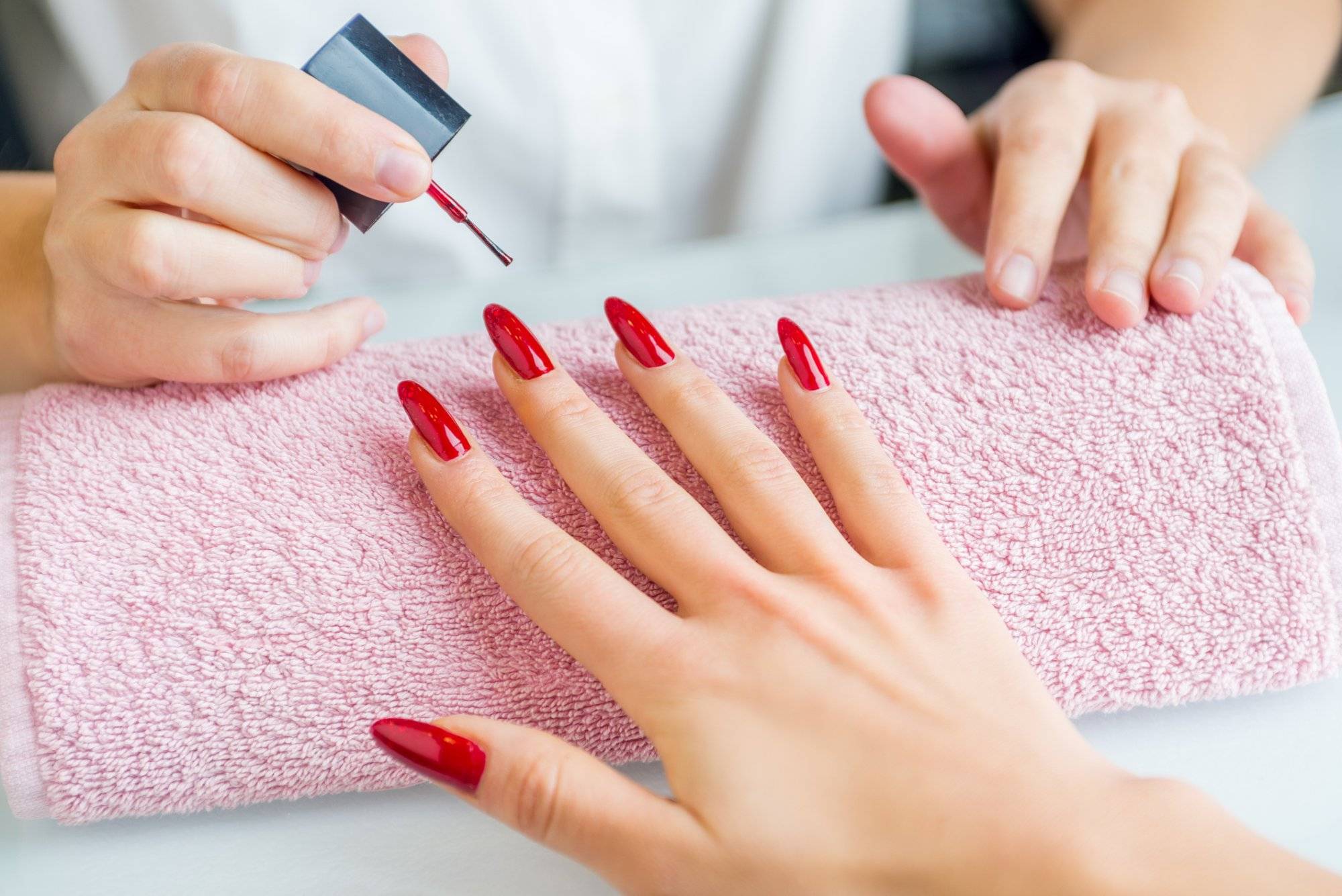 A woman with red painted nails getting a manicure